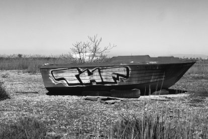 Una barca abandonada en un descampat vora Alcarràs on també s’acumula brutícia de tota mena