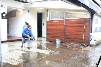 Una dona netejant una de les terrasses afectades a Cadaqués