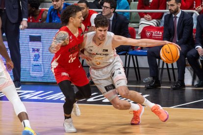 El alero de Hiopos Lleida Oriol Paulí (d), controla el balón ante la presión del ala base estadounidense de UCAM Jonah Radebaugh (i), durante el partido de la décimo sexta jornada de la liga Endesa que están disputando este domingo en el Palacio de los Deportes de Murcia.