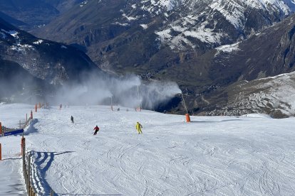 Esquiadors baixant per una pista on funcionen canons de producció de neu a Baqueira