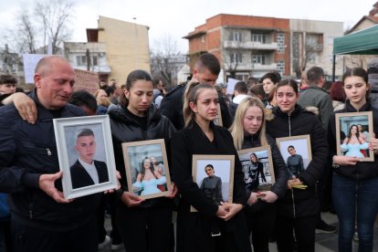 Familiars amb fotos dels seus éssers estimats morts en l’incendi durant una protesta a Skopje. - EFE/EPA/GEORGI LICOVSKI