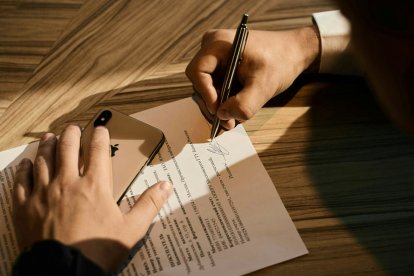 Una persona firmando un documento.