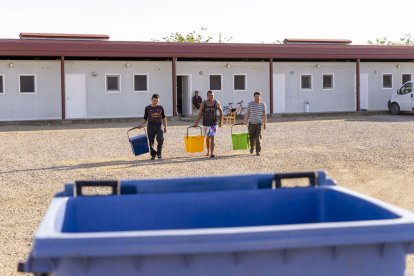 Treballadors de temporada de l’alberg d’Alcarràs a l’esplanada veïna amb cubells de la selectiva. - MAGDALENA ALTISENT