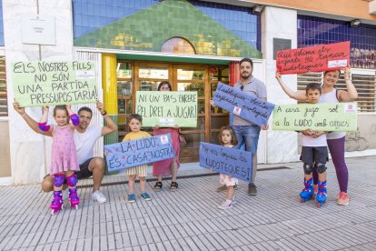 Famílies, davant la ludoteca amb algunes de les pancartes que preparen per a la protesta. - JORDI ECHEVARRIA