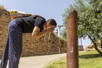 Una dona es refresca en una font a Lleida.