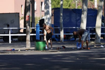 Dos persones netejant-se a la font que han habilitat al costat del pavelló 3 que fa d’alberg. - JORDI ECHEVARRIA