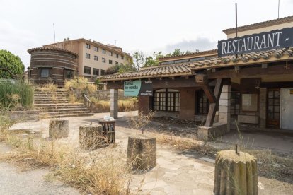 El restaurant a la venda al costat de Masia Salat, al fons, està ple de vegetació i molt degradat. - PAU PASCUAL PRAT