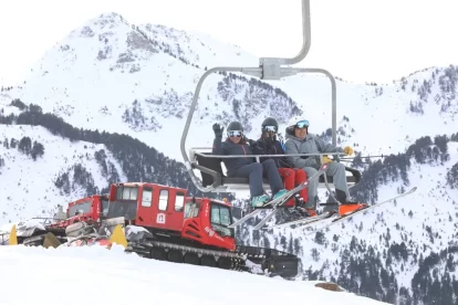 Un grup d’esquiadors en un remuntador de Baqueira-Beret amb màquines trepitjaneu al fons. - EDGAR ALDANA