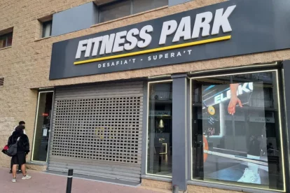 Dos clients del gimnàs llegint la nota que el local estaria tancat fins a, almenys, el dia 19. - SCD