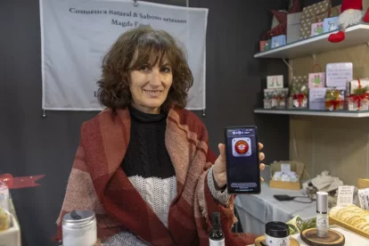 Una comerciant del mercat de Nadal de la plaça Catedral mostra l’aplicació DragAlert. - JORDI ECHEVARRIA