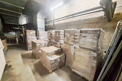 Imatge dels palets amb menjar, llits i estris de lavabo personal en un magatzem. A dalt a la dreta, anvers i revers d’una bossa amb una ració de menjar. - SCD