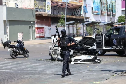 Un policia vigila prop d’un cotxe incendiat a Guadalajara, capital de l’estat de Jalisco. - EUROPA PRESS / CONTACTO / DIANA MARQUEZ