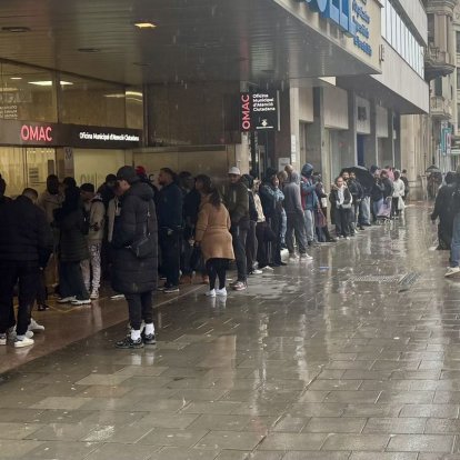 Desenes de persones, fent cua ahir davant de l’OMAC, malgrat la pluja. - MARC CARBONELL