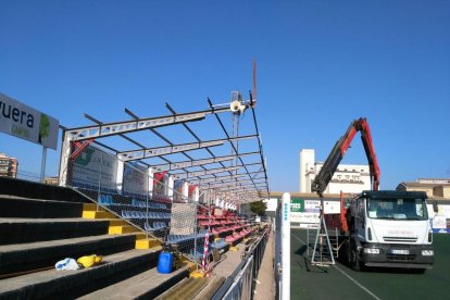 Operaris retiren, amb vestits especials, els trossos de coberta que contenen amiant.