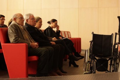Fèlix Millet, sentado delante de su silla de ruedas, junto a Jordi y Gemma Montull en el banquillo de los acusados en el juicio.