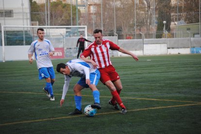 El local Edu Raya conduce un balón ante la oposición de un jugador rival durante un lance del partido.