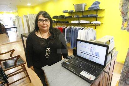 Meritxell Montagut, a la seua botiga i mostrant la pàgina web de l'establiment
