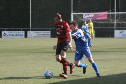 Un jugador del EFAC pelea un balón con un jugador del Sants con el colegiado al fondo.
