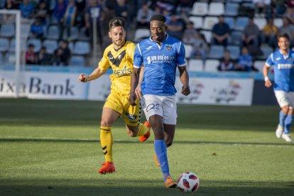 Fernando Cano és frenat per un defensa del Badalona dins de l’àrea, en una acció atacant del Lleida.