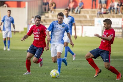 Liberto conduce el balón ante la presión de dos rivales.