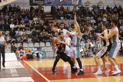 Ablaye Mbaye i Juampi Sutina lluiten per un rebot amb un jugador del Peñas Osca.