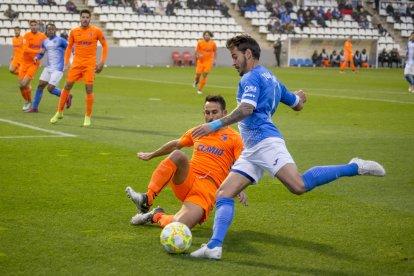 Joan Oriol centra el balón presionado por Carlos Barreda.
