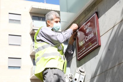 Un operario coloca la placa con el nombre de Neus Català.