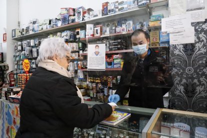 Un comerciant atén amb màscara i darrere d’una mampara.