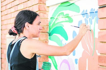 La artista Lara Costafreda pintando el exterior de la escuela.