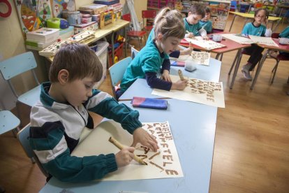 Los escolares muestran letras mayúsculas que escribieron con cañas y tinta.