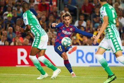 Griezmann dispara a puerta entre dos futbolistas del Betis.