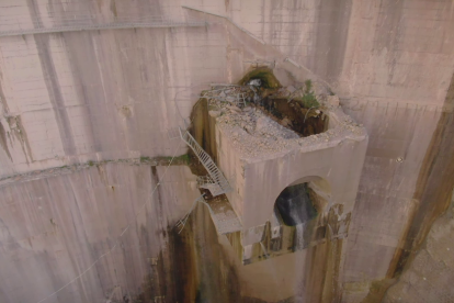 Las obras para colocar redes y garantizar la sujeción de la ladera al lado de la presa del pantano de Canelles y, a la derecha, el desagüe de fondo que se tiene que reparar.