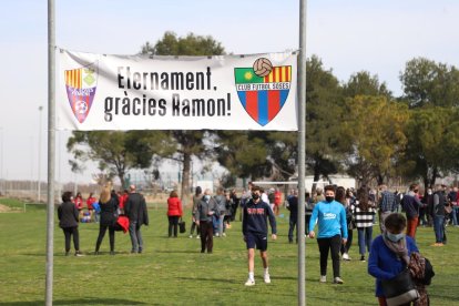 Una jugadora del Soses Femení entrega a la família una samarreta firmada per tota la plantilla i un ram de flors.