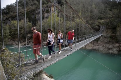 Un grupo de turistas cruzando la pasarela colgante de Mont-rebei.