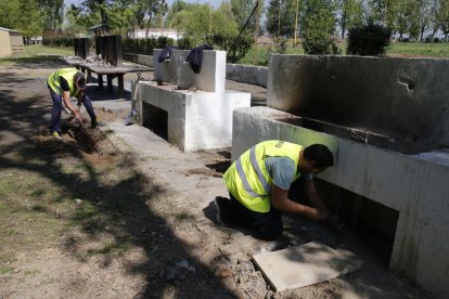 Dos operarios trabajando en la mejora de la zona de las barbacoas, que sigue teniendo mucho uso.