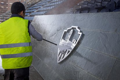 Un operari neteja amb una mànega a pressió els excrements de l’escut de la llotja del Camp d’Esports.