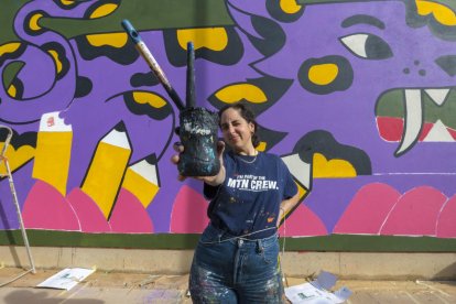 Amaia Arrazola pinta un mural en la fachada de la Escuela Frederic Godàs.