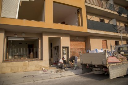 Una entrada al edificio sin puerta, con instalaciones eléctricas rotas y una tapia perforada.