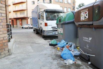 Cajas al lado de un contenedor de papel y cartón en la plaza Santa Maria Magdalena (Clot).