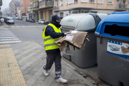 Un operario de la brigada recoge la basura de la calle mientras otro registra la incidencia o “punto negro” con el teléfono móvil.