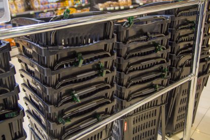Una empleada muestra las alarmas en una de las cestas y carros en el supermercado.