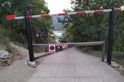 Un vigilant controla l’entrada de vehicles a la zona de la Platgeta de Camarasa i cobra cinc euros.