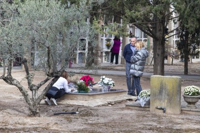 Anglesola. Una familia limpiando y colocando flores en una tumba.