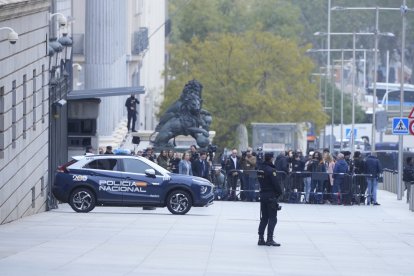 Un agente de la Policía Nacional se mira las vallas que blindan el Congreso de los Diputados.