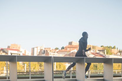 sensesotre. Dos persones dormen sota una passarel·la sobre riu Segre a Lleida mentre una tercera fa esport.