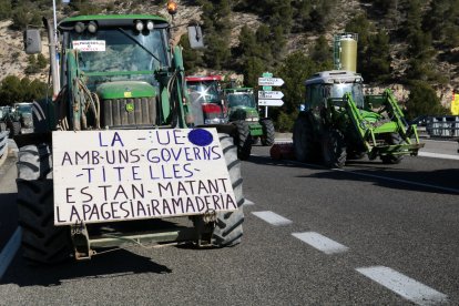 Un tractor porta una pancarta que carrega contra les directrius europees al tall de la pagesia a la C-14 a Ciutadilla, a l'Urgell
