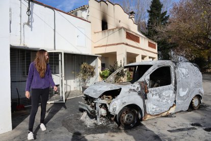 Anna Clop mostra la furgoneta calcinada, i al fons es poden veure restes de l’incendi a la segona planta de la casa.