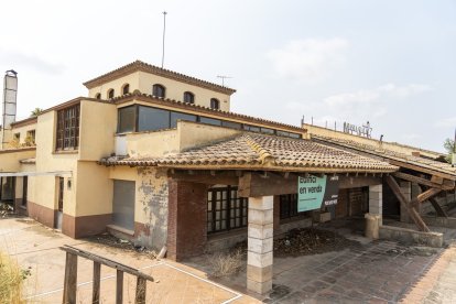 El restaurant a la venda al costat de Masia Salat, al fons, està ple de vegetació i molt degradat.
