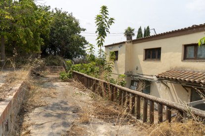 El restaurant a la venda al costat de Masia Salat, al fons, està ple de vegetació i molt degradat.
