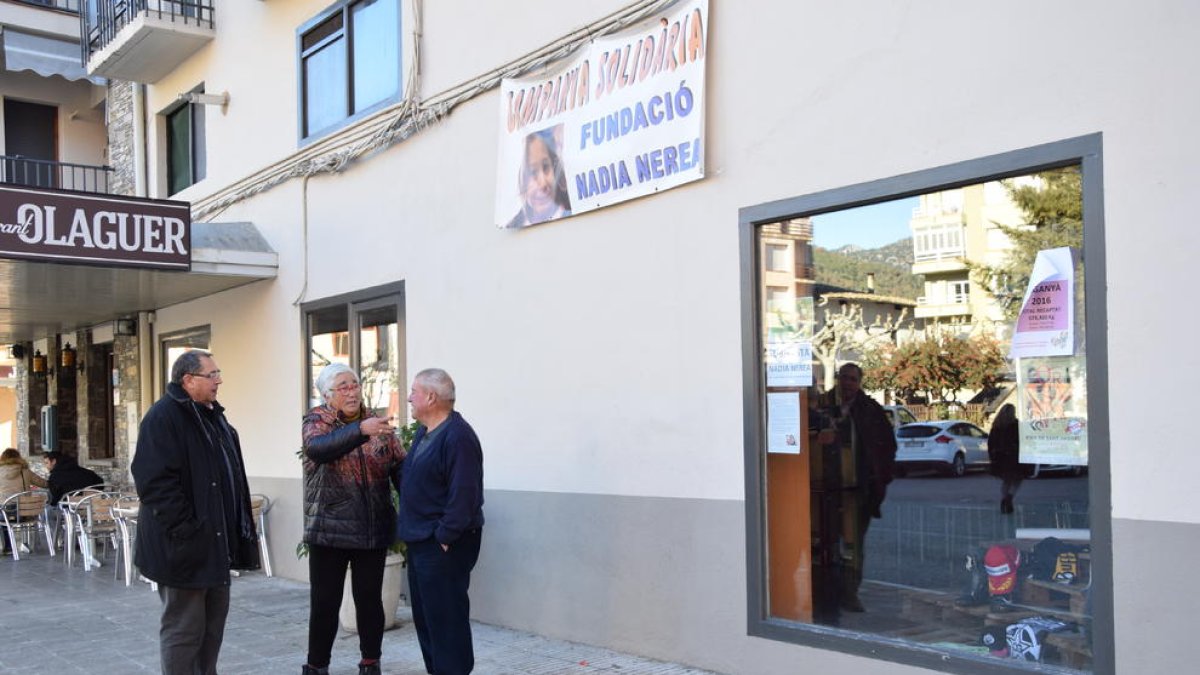 L’alcalde d’Organyà i dos veïns, ahir, sota una de les pancartes penjades al municipi per recaptar fons.